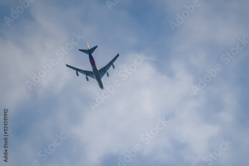 Four-engine passenger airplane under white clouds