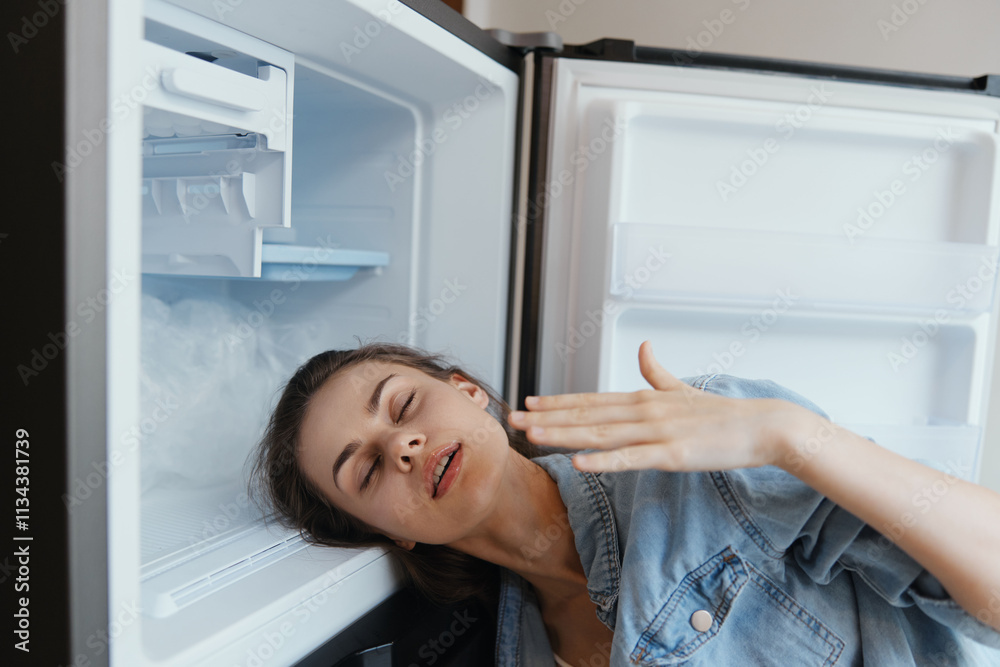 A distressed woman in casual denim attire leaning against an open refrigerator, expressing discomfort and fatigue, highlighting issues of mood and energy depletion