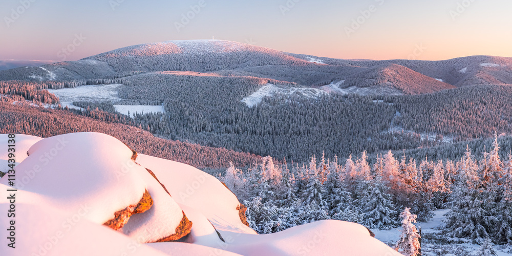 Eastern Sudetes, View of snowy mountain range from hiking trail during winter hike in the mountains, viewpoint of wide winter landscape in the mountains at sunset.