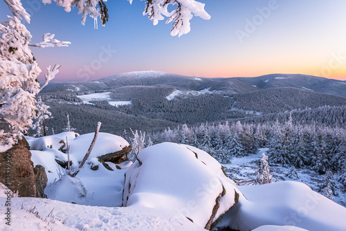 Eastern Sudetes, View of snowy mountain range from hiking trail during winter hike in the mountains, viewpoint of wide winter landscape in the mountains at sunset.