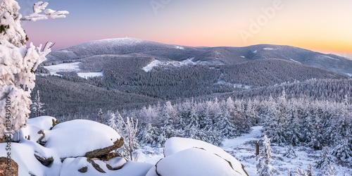 Eastern Sudetes, View of snowy mountain range from hiking trail during winter hike in the mountains, viewpoint of wide winter landscape in the mountains at sunset.