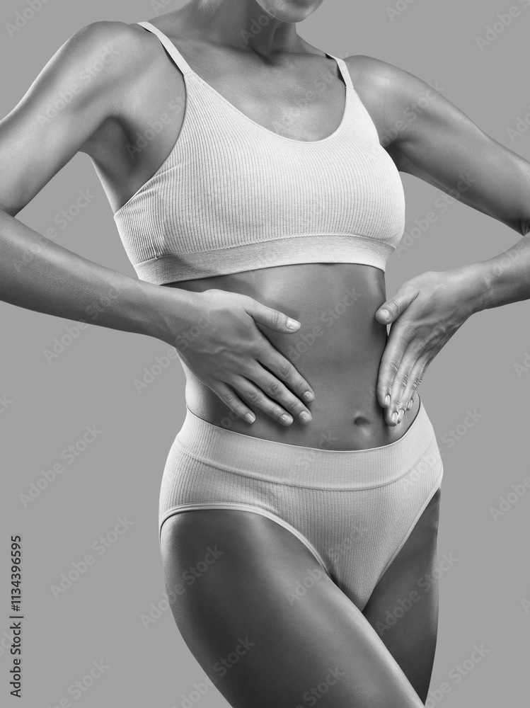 Fototapeta premium A slender swarthy woman in underwear on a white background. Healthy lifestyle, sport and diet.