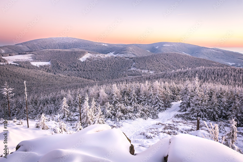 Eastern Sudetes, View of snowy mountain range from hiking trail during winter hike in the mountains, viewpoint of wide winter landscape in the mountains at sunset.
