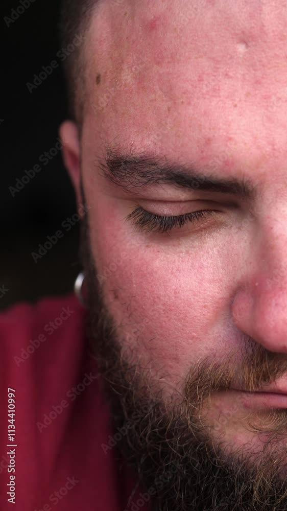 Vertical: The half-face of a young man with a dark beard, giving a stern and disapproving look straight at the camera. His half expression conveys deep emotions. Vertical: The half-face of a young man with a dark beard, giving a stern and disapproving look straight at the camera. His half expression conveys deep emotions.
