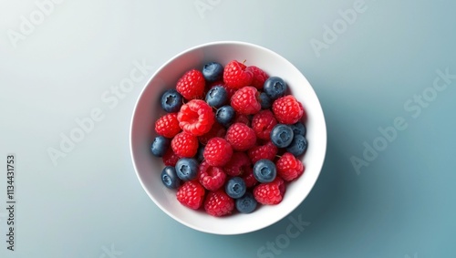 A bowl of raspberries and blueberries on a blue background