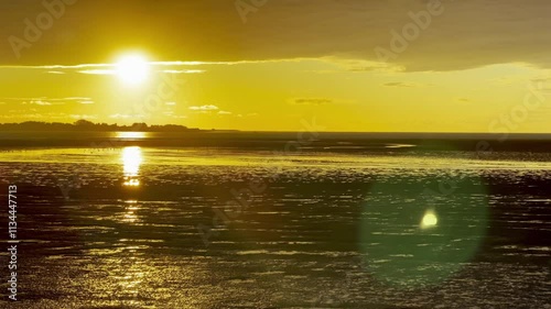 Vibrant Sunset Reflecting on the Bay of Somme’s Mudflats in October, Capturing the Golden Glow, Rippling Tidal Patterns, and a Dramatic Horizon from Le Crotoy photo