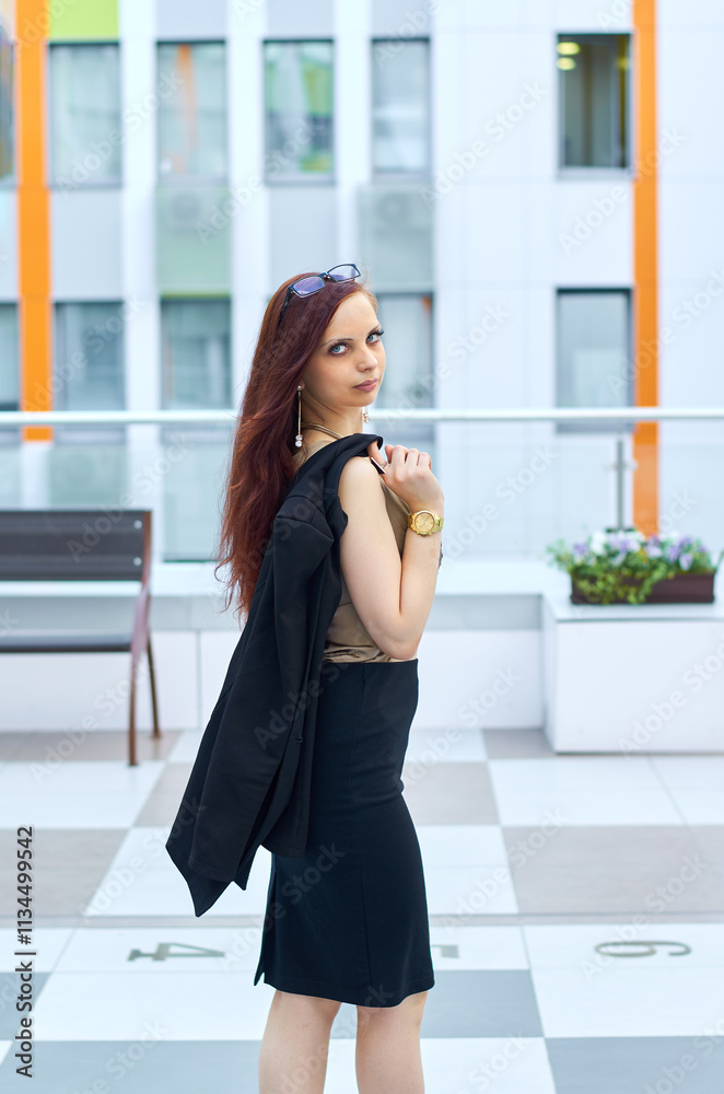 Portrait of a beautiful woman walking in the city. She is wearing a black dress and her chic hair is combed back. Leisure concept. Portrait of a beautiful woman walking in the city. She is wearing a black dress and her chic hair is combed back. Leisure concept.