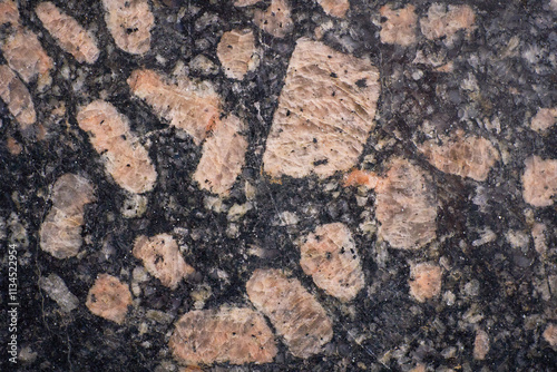 Close-up view of a polished granite surface revealing feldspar crystals embedded in a dark matrix, showcasing natural stone texture.