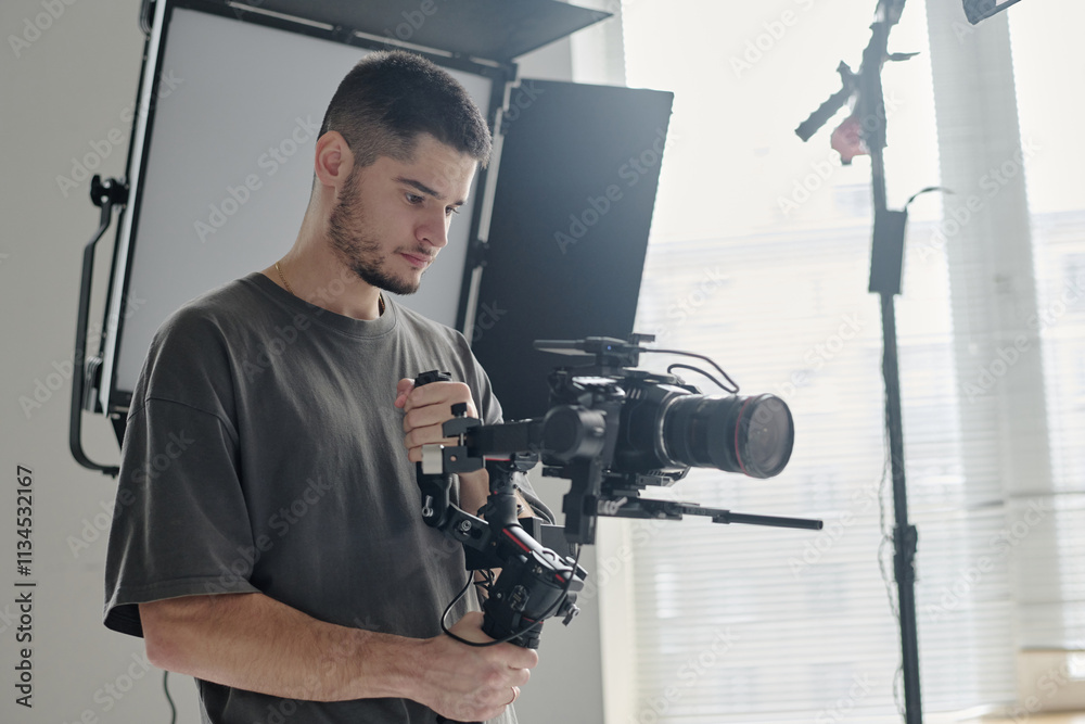 © AnnaStills - Medium close up of talented operator with massive camera enjoying shooting scene at studio © AnnaStills - Medium close up of talented operator with massive camera enjoying shooting scene at studio