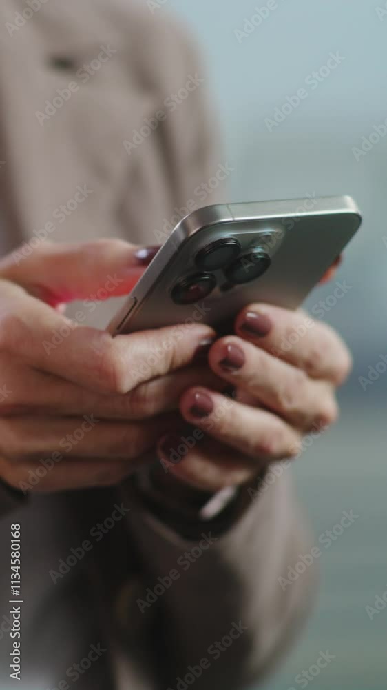 Vertical shot of successful businesswoman chatting with business partner in messenger app or consulting client on mobile phone. Female marketing specialist works in modern office of E-commerce company