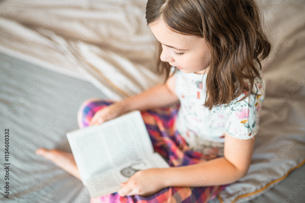 Child reads a book in a bedroom. Little girl reads a bedtime story in her room. Education concept. Child reads a book in a bedroom. Little girl reads a bedtime story in her room. Education concept.
