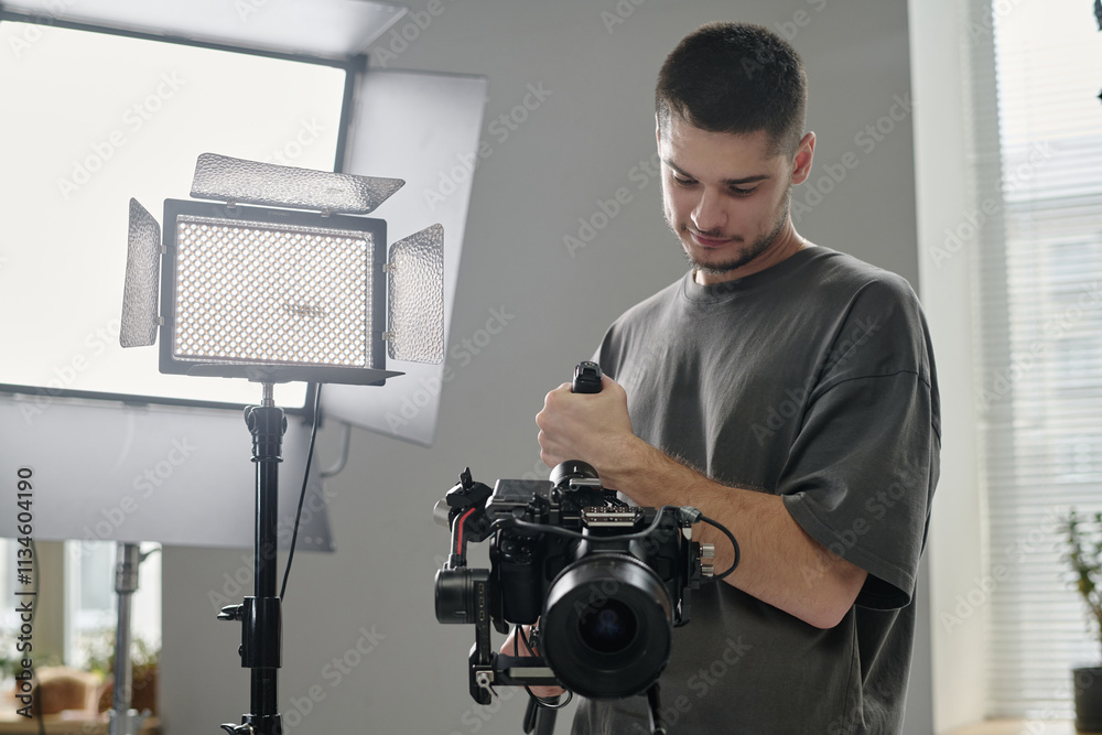 Low angle shot of Caucasian talented operator using professional massive camera at studio Low angle shot of Caucasian talented operator using professional massive camera at studio