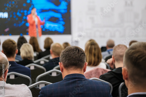 Group of people watching a speaker in a formal setting, ideal for education or corporate content