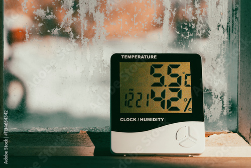 Electronic device to check temperature and humidity in closed area near window in winter sunny day, closeup