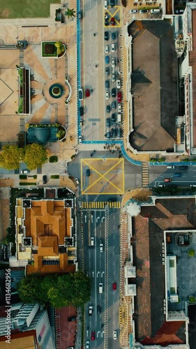 Top view of cars drives to the road. Aerial view of a busy city intersection with marked traffic lanes, vehicles, and crosswalks Opening, establishing shot, hyper lapse, time lapse. Vertical video