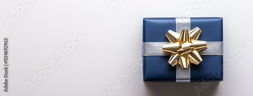 Holiday gift box wrapped in navy blue color paper with gold and silver ribbons. background in white color. copy space photo