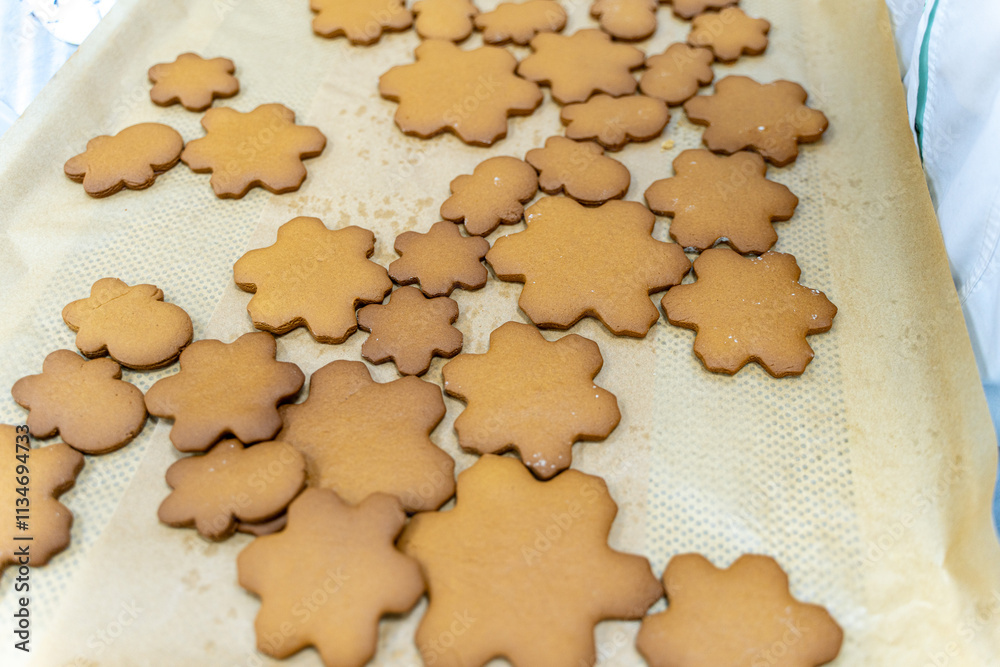 Snowflake-shaped cookies are ready to be decorated with frosting on baking paper. The process of cooking a New Year's or Christmas treat, recipe. Snowflake-shaped cookies are ready to be decorated with frosting on baking paper. The process of cooking a New Year's or Christmas treat, recipe.