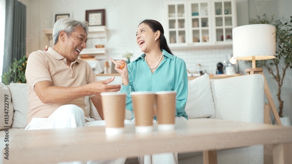 Happy elderly couple enjoying a ball toss game together at home, practicing coordination and cognitive skills for healthy aging. Grandfather and grandmother throwing ping pong in the bowl. Myrmidon. Happy elderly couple enjoying a ball toss game together at home, practicing coordination and cognitive skills for healthy aging. Grandfather and grandmother throwing ping pong in the bowl. Myrmidon.