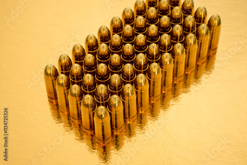 Closeup of 50 9mm pistol cartidges in rows of five on a golden background. photo