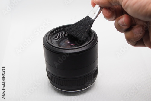 hand cleaning the 
Cleaning the camera lens with a black brush.
positioned in front of the lens.
 photo