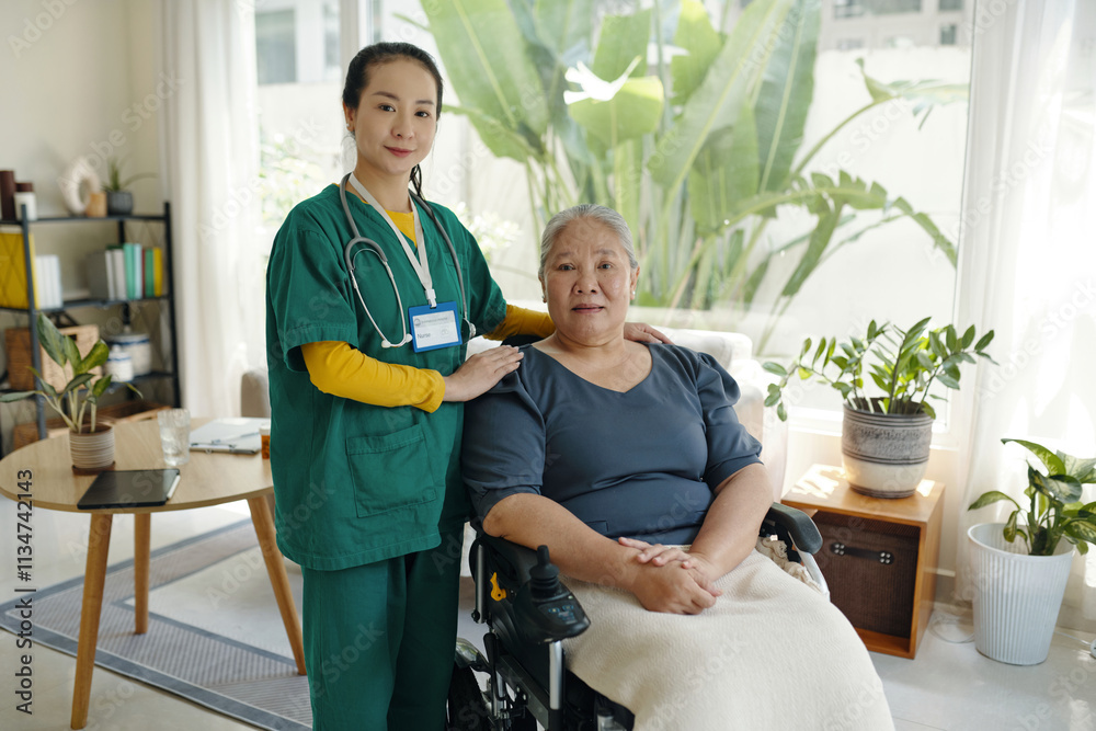 Obraz premium Portrait of caregiver standing together with senior patient in wheelchair