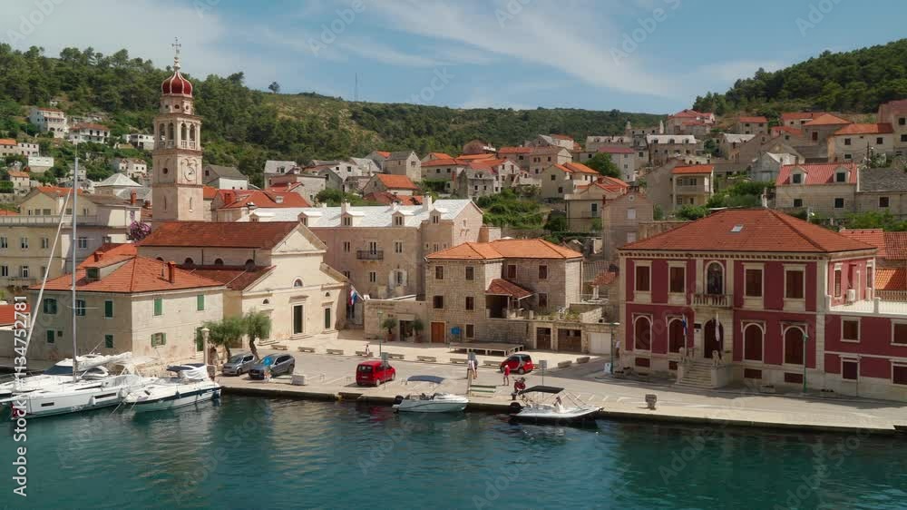 The waterfront promenade of a tourist town on a hillside by the sea. Stone houses with tile roofs and charming streets in the port town of Pucisca (Pučišća) on the island of Brac (Brač), Croatia. The waterfront promenade of a tourist town on a hillside by the sea. Stone houses with tile roofs and charming streets in the port town of Pucisca (Pučišća) on the island of Brac (Brač), Croatia.