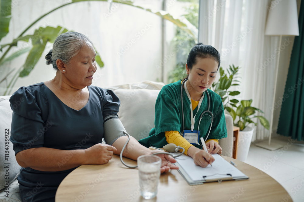 Nurse doing medical exam at home while visiting to senior woman Nurse doing medical exam at home while visiting to senior woman