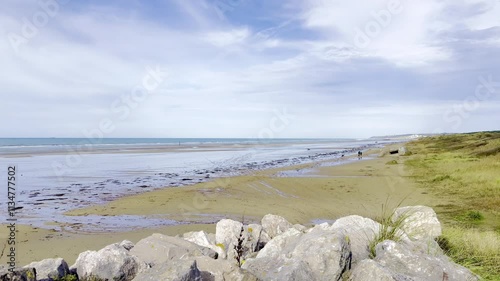 Historic Bunker and Scenic Shoreline of Dannes Beach in Autumn, Featuring Dog Walkers on the Sandy Coast, Tidal Reflections, and a Coastal Village Under Blue Sky