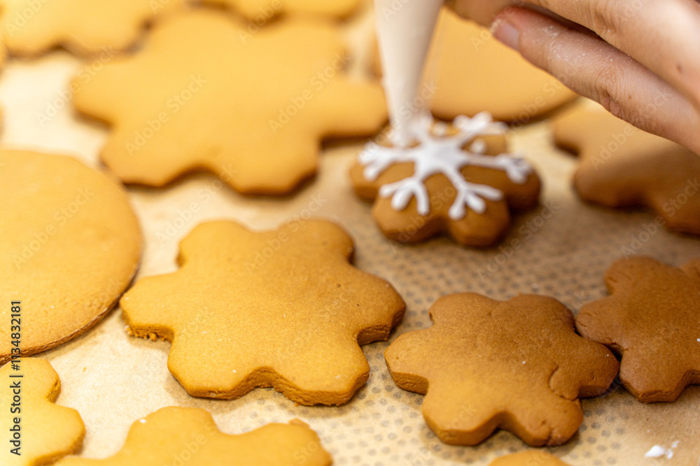 A pastry chef hand with a cooking bag decorates cookies in the form of a snowflake. Gingerbread, New Year or Christmas cookie decor. A pastry chef hand with a cooking bag decorates cookies in the form of a snowflake. Gingerbread, New Year or Christmas cookie decor.