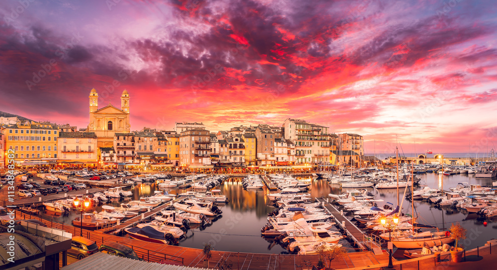 Vibrant marina of Bastia, Corsica, featuring a picturesque harbor, Mediterranean architecture, and a stunning sunset over luxury yachts.