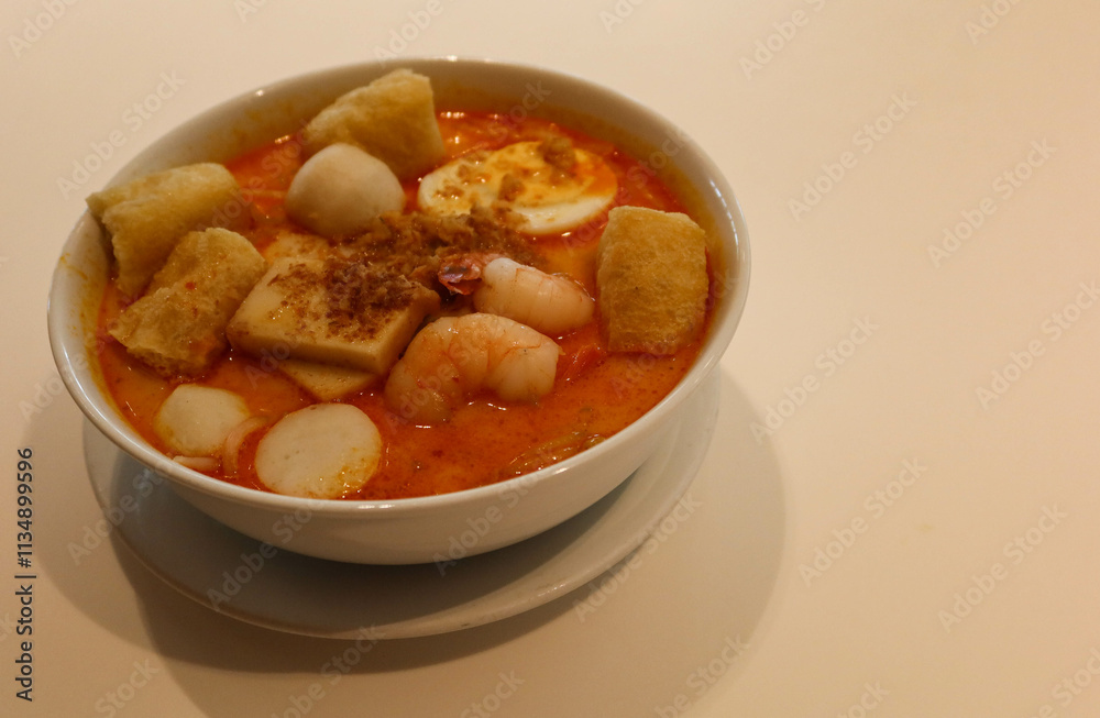 close up of Singaporean Malaysian soup laksa noodles with fishballs, tofu bean curd, prawns, shrimps and fish slice close up of Singaporean Malaysian soup laksa noodles with fishballs, tofu bean curd, prawns, shrimps and fish slice