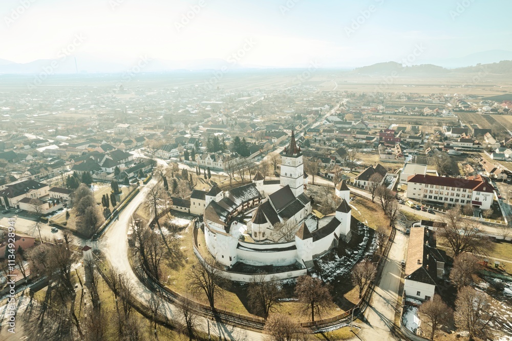 Obraz premium Majestic aerial views capture the beauty of Piatra Craiului and Rasnov, showcasing the ancient fortifications and serene winter landscape of Brasov, Romania under a bright sky