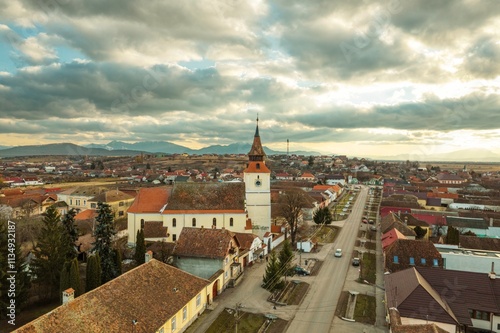 Explore the stunning aerial vista of Piatra Craiului mountains coupled with Rasnov and Plaiul Foii, revealing a tranquil village adorned with historical architecture and lush greenery photo