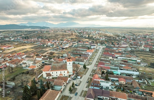 Views from above showcase the quaint village of Rasnov, nestled in the Piatra Craiului region of Brasov, highlighting its distinctive homes and expansive farmland