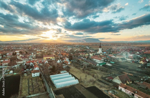 Golden sunlight bathes the quaint villages of Rasnov and Plaiul Foii, casting enchanting shadows upon rooftops and fields photo