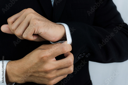 Close-up of a man in a tux fixing his cufflink and make a groom.