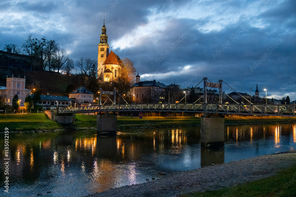 Obraz premium Night view of Our Lady of the Assumption church, Kirche Maria Himmelfahrt, on the foothills of the Monchsberg in Salzburg, Austria, along Salzach River