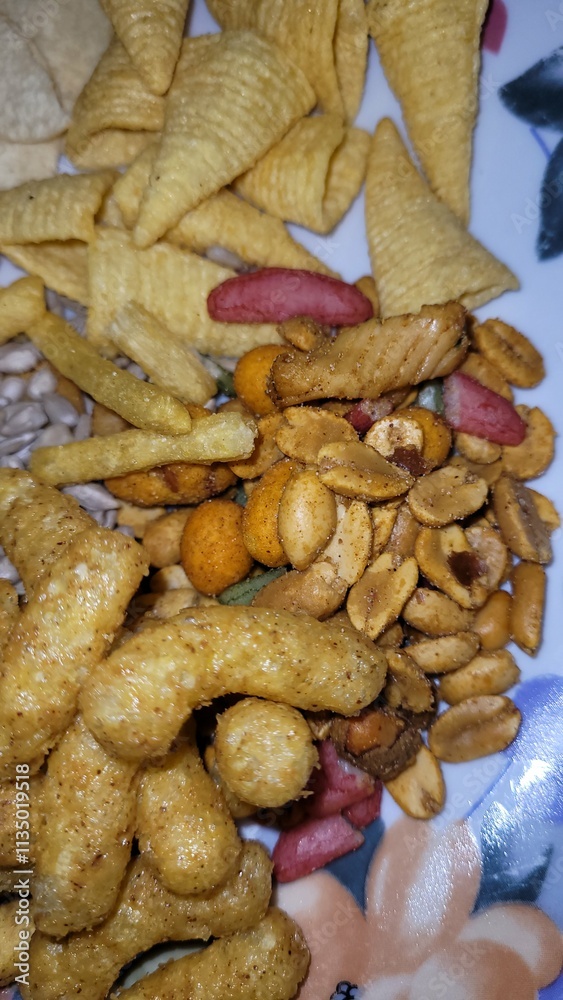 Fototapeta premium Très belle assiette d'apéritifs composé de biscuits avec frites, tuiles et cornets, maïs, gâteaux de riz, grains, cacahuètes soufflées