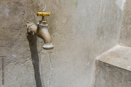 Spout with trough, sink with faucet, pipe and cement sink. Washing, drinking water, open water, open faucet, open spout. Water draining with open sink spout. photo