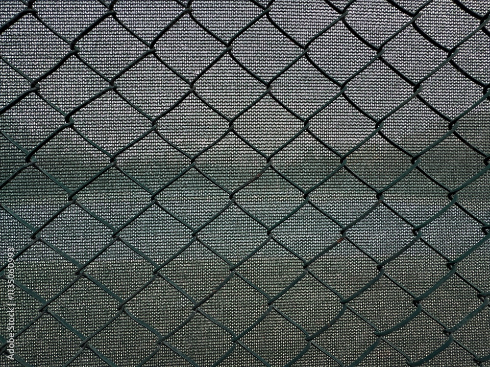 Fototapeta premium Close-up of wire mesh fence. Green sun protection and green wire fence. Safety nets. Green steel wire chain link net fence. Galvanized pvc coated chain link. Garden steel fence background. 