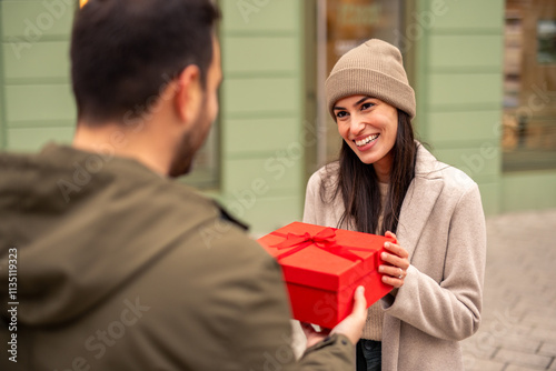 Wallpaper Mural A mid adult Caucasian husband surprises his wife with a red gift box, both smiling warmly. Torontodigital.ca
