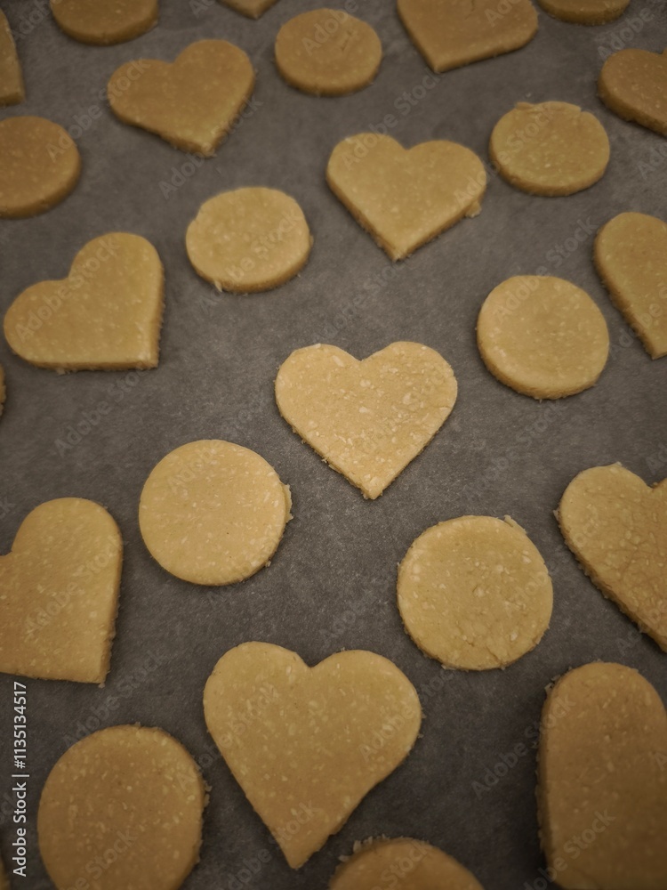 Obraz premium Heart and circle shaped cookies baking on parchment paper for valentine's day