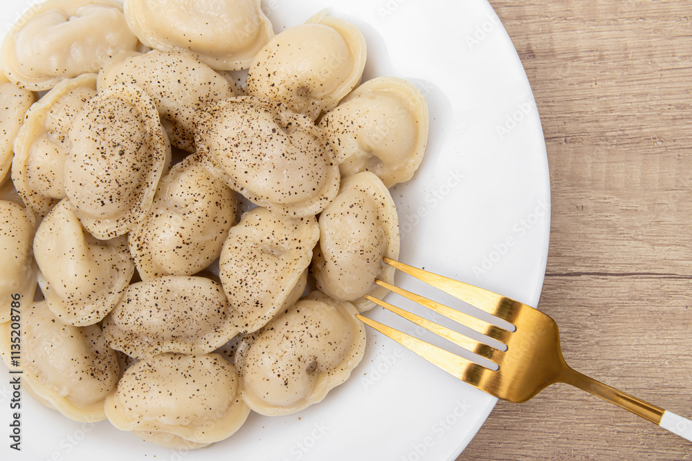 Boiled dumplings with spices in a plate. Golden fork Boiled dumplings with spices in a plate. Golden fork