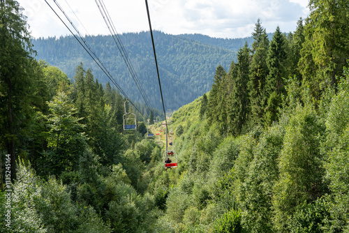 Ski lift in green forest. Cableway in Mountains. Summer nature outdoor trees photo