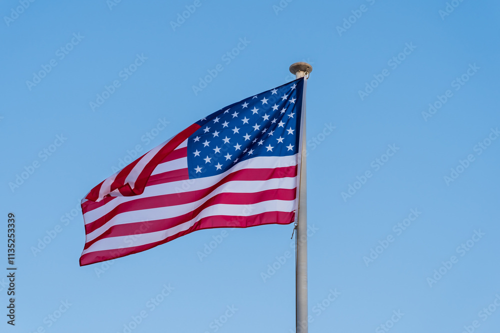  American flag waving in the wind. Stars and Stripes against a blue sky. Symbol of freedom.