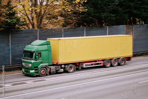 Green Truck Transporting Yellow Standard ISO Shipping Container for Cargo Operations photo