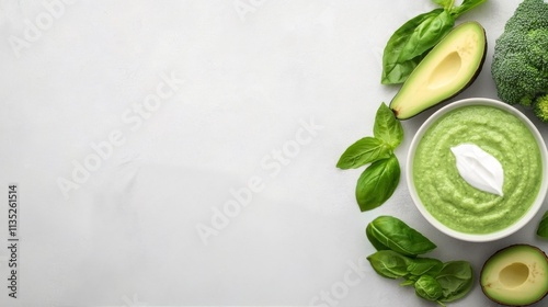 Green vegetable soup with avocado and basil on a light gray table