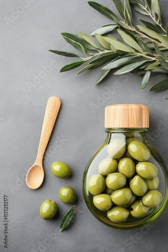 Green olives with leaves arranged on a gray surface in a stylish bowl