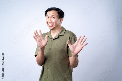 Quadro em tela An Asian man in a green polo shirt reacts with an exaggerated surprised expressi