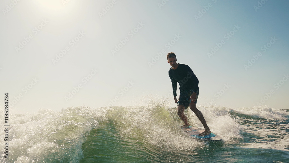 A wakeboarder performs exciting tricks on his board, moving quickly through the water. The footage shows smooth turns, jumps and acrobatics, highlighting the athlete's skill and endurance. Ideal for t A wakeboarder performs exciting tricks on his board, moving quickly through the water. The footage shows smooth turns, jumps and acrobatics, highlighting the athlete's skill and endurance. Ideal for t